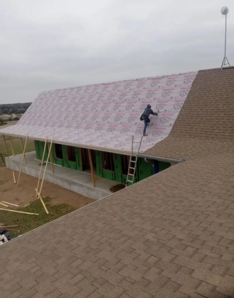 Worker preparing underlayment for a metal roof installation in Mayfield